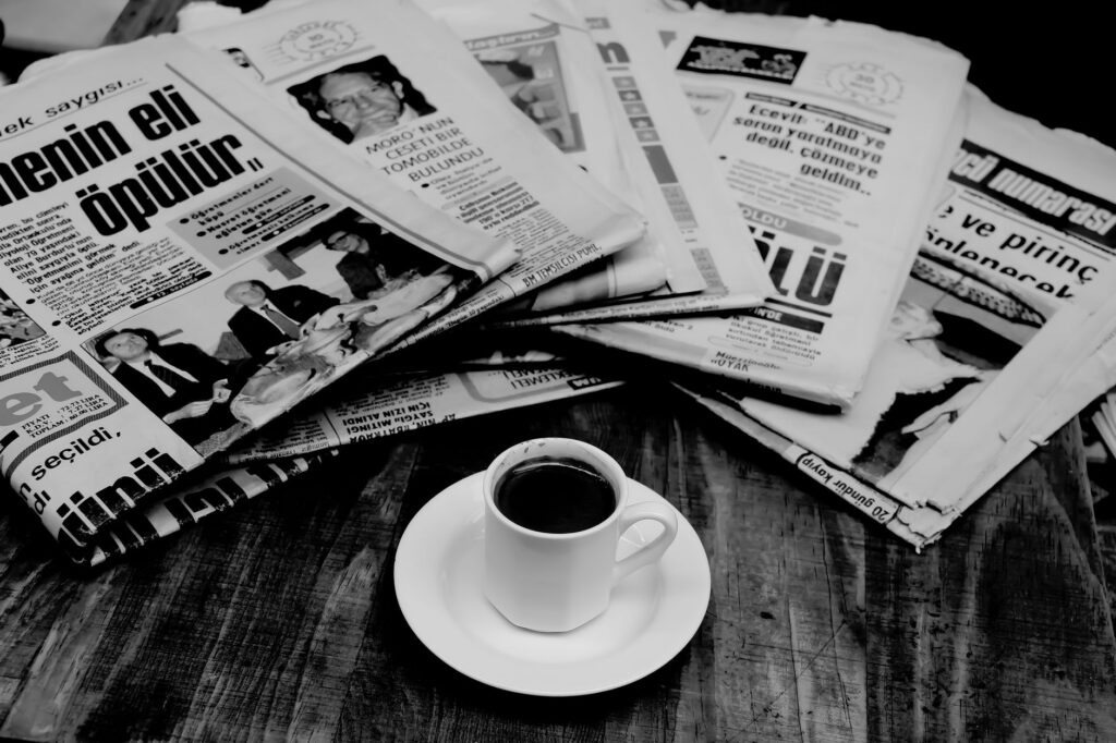 Ziar deschis lângă o ceașcă de cafea pe o masă, într-o dimineață liniștită