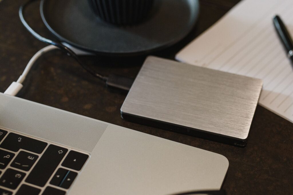 Hard disk extern conectat la un laptop pe un birou, pentru copia de siguranță a lucrărilor